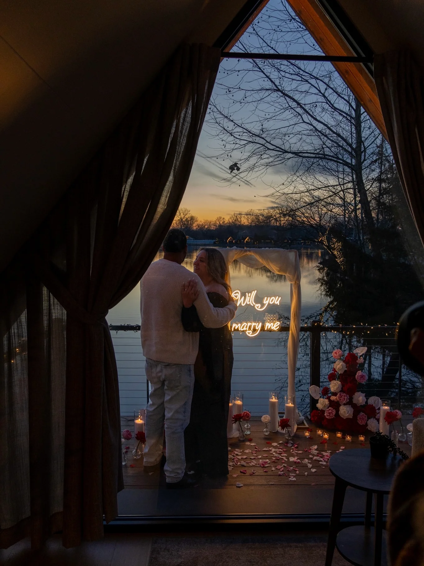 Romantic proposal moment on lakefront cabin deck at sunset